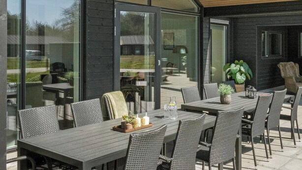 Un espacio de comedor al aire libre con diseño moderno, que incluye una mesa grande y sillas, y vistas del paisaje circundante.
