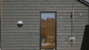 Un edificio moderno con tablones horizontales de madera, una puerta de cristal y un letrero de metal con el número '1'.