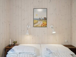 Quarto com duas camas, um quadro pendurado na parede e duas luminárias de parede.