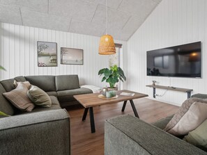 Uma sala de estar moderna com sofá, mesa de centro e televisão fixada na parede.