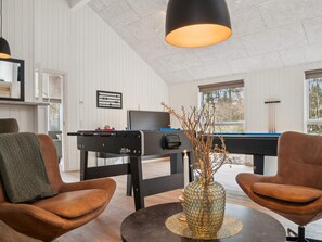 A room with a pool table, two leather chairs, a vase with branches, and a ceiling light fixture. - 5 Star Holiday Home in Aakirkeby (Akirkeby)