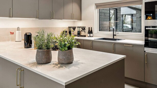 A modern kitchen with grey cabinets, a large island with potted plants, a window with a view, and built-in appliances. - 5 Star Holiday Home in Sydals (Sydals)