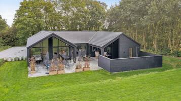 Une maison moderne dotée d’un grand patio, d’un espace repas et d’une piscine.
