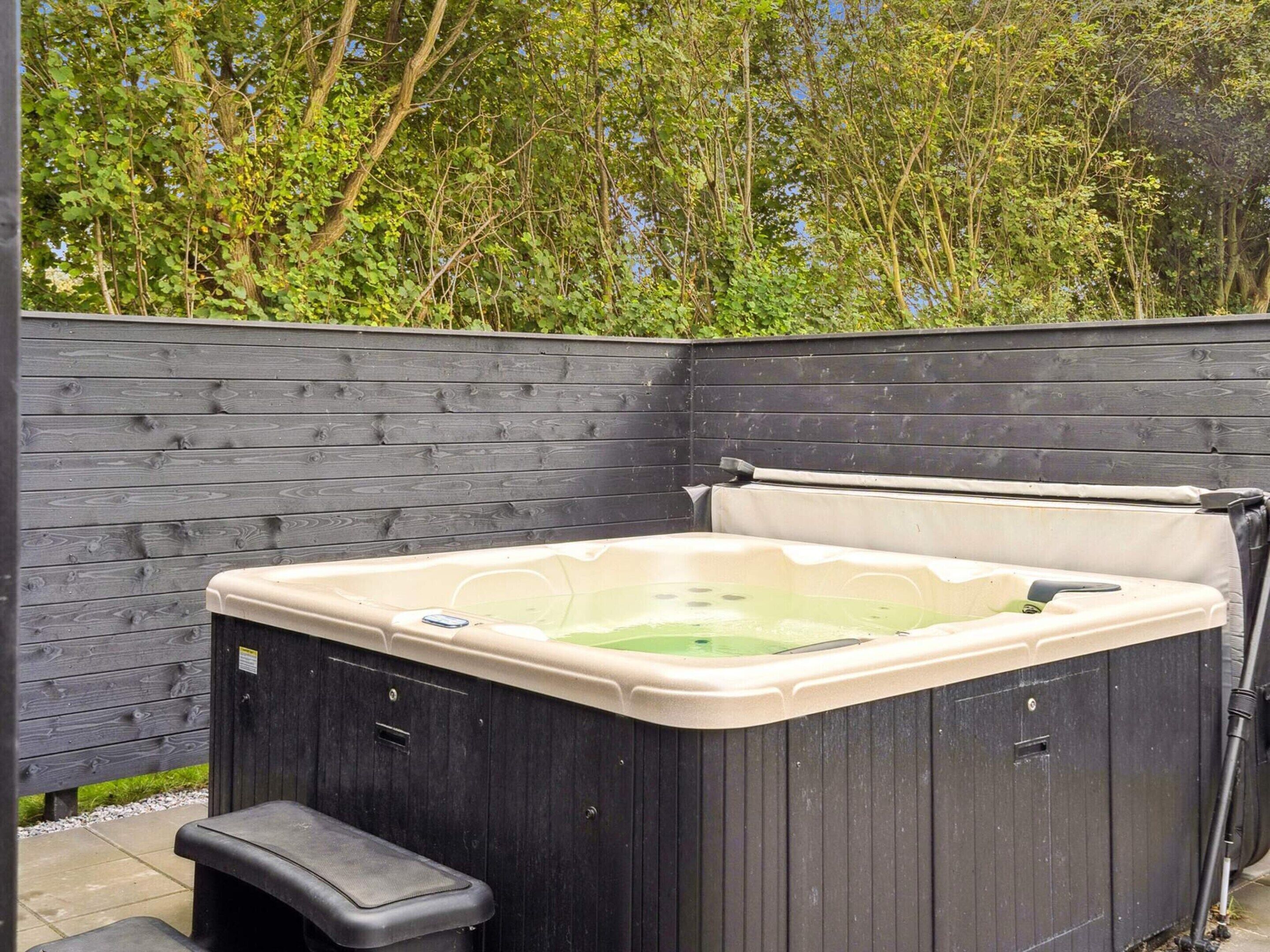Un bain à remous avec une terrasse en bois et une clôture en bois en arrière-plan.