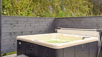 Un bain à remous avec une terrasse en bois et une clôture en bois en arrière-plan.