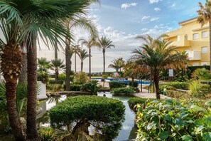 A hotel courtyard with palm trees, a small pond, and a pool. - Cozy Apartment in La Cala de Mijas (Mijas)