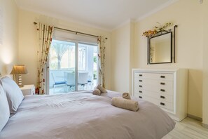 A bedroom with a large bed, a dresser, a mirror, and a view of the outdoors. - Cozy Apartment in La Cala de Mijas (Mijas)