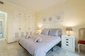 A bedroom with a large bed, two bedside tables with lamps, a wardrobe, and a wall with decorative art. - Cozy Apartment in La Cala de Mijas (Mijas)