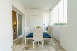 A balcony with two wicker chairs and a table, a sliding glass door, and a view of greenery. - Cozy Apartment in La Cala de Mijas (Mijas)