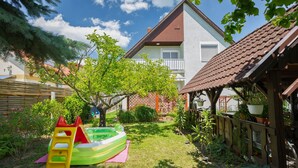 A backyard with a slide, a small tree, and a wooden playhouse. - Noisette by Interhome (Balatonkeresztur)