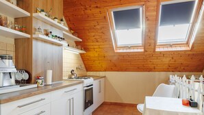 A kitchen with white cabinets, a stove, and a table with chairs. There are two skylights and a window. - Noisette by Interhome (Balatonkeresztur)