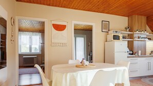 A modern kitchen with white cabinets, a microwave, and a sink. There is a dining area with a white table and chairs. - Noisette by Interhome (Balatonkeresztur)