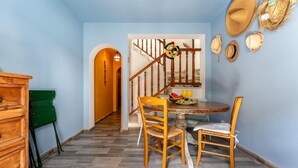 A dining area with a wooden table and chairs, a staircase with a railing, and a wall decorated with hats. - Faro's Casa Evita - Estepona Old Town (Estepona)