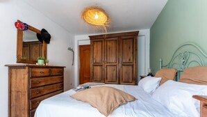 A bedroom with a bed, wooden wardrobe, dresser, and a mirror. - Faro's Casa Evita - Estepona Old Town (Estepona)