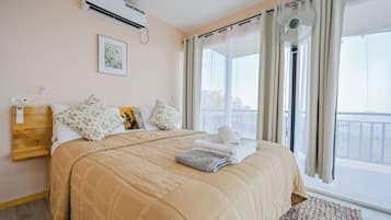 Hotelkamer met een bed, nachtkastje, wandairco, raam met gordijnen en uitzicht.