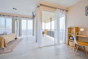 Ein modernes Schlafzimmer mit einem Bett, einem Holzstuhl, einem kleinen Tisch und einem Balkon mit Blick.