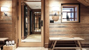 A wooden interior with a wooden bench, a table, and a pair of shoes on the floor. - Lech Lodge - LEGENDARY (Lech am Arlberg)