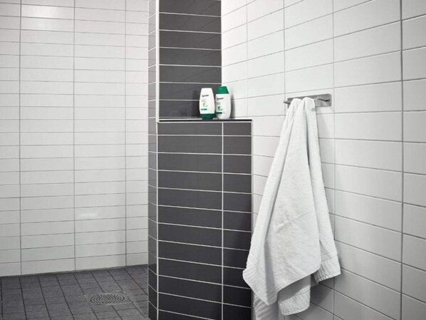 A bathroom with white and dark grey tiles, a shower area, and a towel rack with a white towel. - 6 Person Holiday Park Home in Goteborg (Gothenburg)
