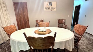 A conference room with a round table, six wooden chairs, a chandelier, and a sign reading "BLACK HILLS STATE UNIVERSITY". - Authentic Spearfish Home 1 Block from Black Hills State-- Sleeps 8 (Spearfish)