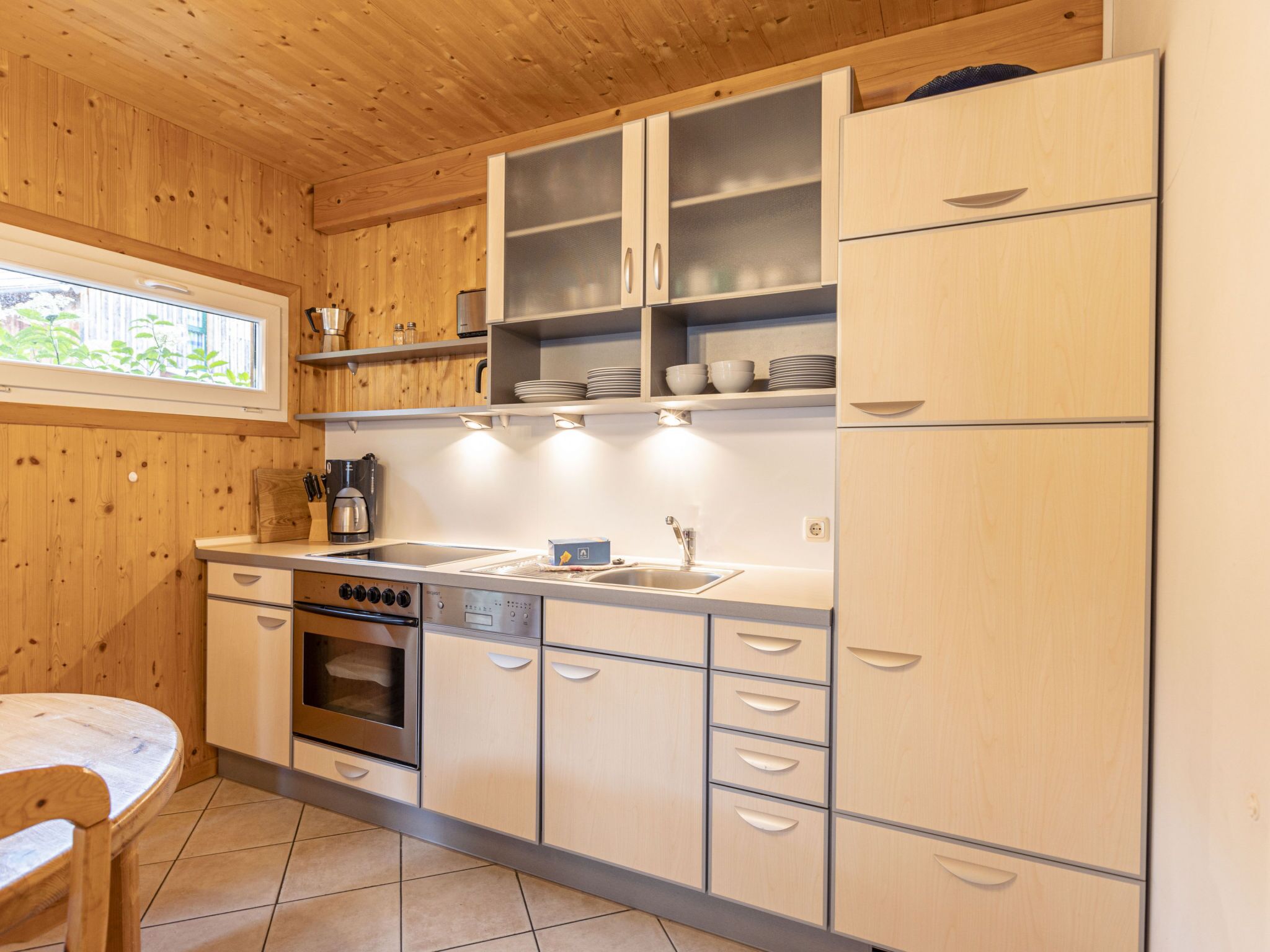 Una cocina moderna con paredes de madera, una estufa de acero inoxidable, un lavamanos y armarios.