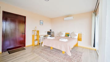 Une chambre à coucher avec un lit, un bureau, une armoire, une porte et une fenêtre.