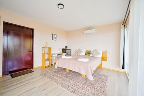 Une chambre à coucher avec un lit, un bureau, une armoire, une porte et une fenêtre.