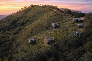 A hillside with three cabins, each with a separate entrance and a small porch.