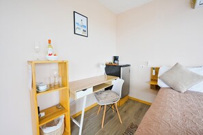 A compact bedroom with a bed, a desk, and a chair.