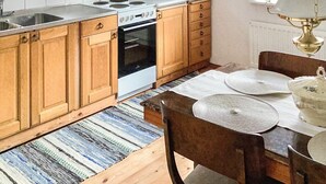 A kitchen with wooden cabinets, a stove, a microwave, and a dining table with placemats. - 4 Star Holiday Home in Munka-ljungby (Munka-Ljungby)