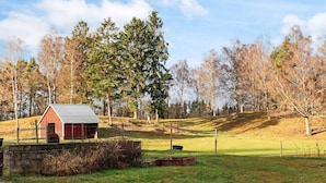 A red barn with a metal roof, surrounded by a grassy field and trees. - 4 Star Holiday Home in Munka-ljungby (Munka-Ljungby)