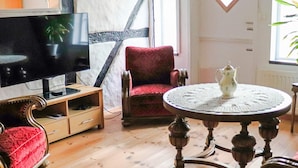 A living room with a television, a red armchair, a wooden coffee table, and a white tablecloth. - 4 Star Holiday Home in Munka-ljungby (Munka-Ljungby)