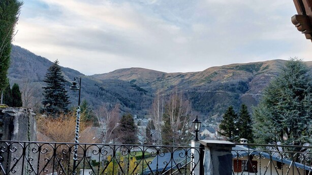 A balcony with wrought iron railings overlooking a mountainous landscape with houses and trees. - Traditional chalet dating from the 70s, fully renovated, sleeps up to 15 people (SAINT LARY SOULAN)