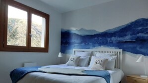 A bedroom with a bed, a nightstand, a window, and a wall mural. - Traditional chalet dating from the 70s, fully renovated, sleeps up to 15 people (SAINT LARY SOULAN)