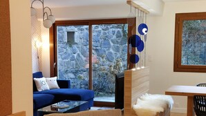 A modern living room with a blue sofa, a wooden coffee table, and a dining area with a white table and black chairs. - Traditional chalet dating from the 70s, fully renovated, sleeps up to 15 people (SAINT LARY SOULAN)