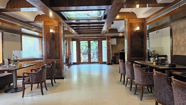 A spacious dining area with wooden beams, multiple tables, and chairs. - Vibe Vacation Hotel, Visakhapatnam – Stay in the Heart of the City (Visakhapatnam)
