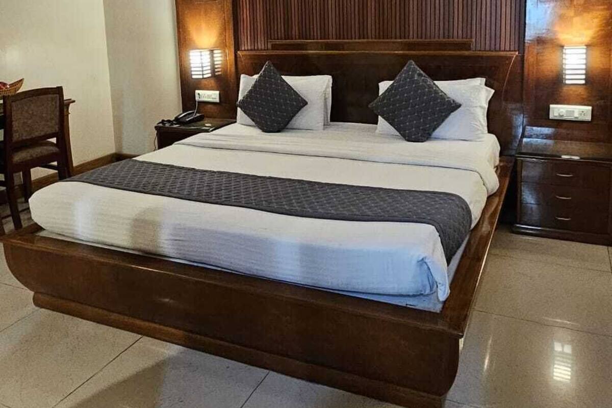 Een groot bed met een houten hoofdeinde, twee nachtkastjes en een plafondventilator.
