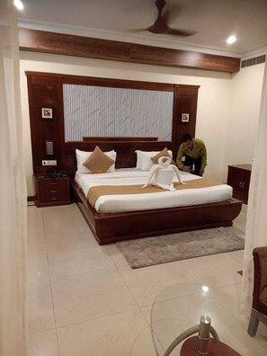A bedroom with a large bed, wooden headboard, bedside tables, and a ceiling fan.