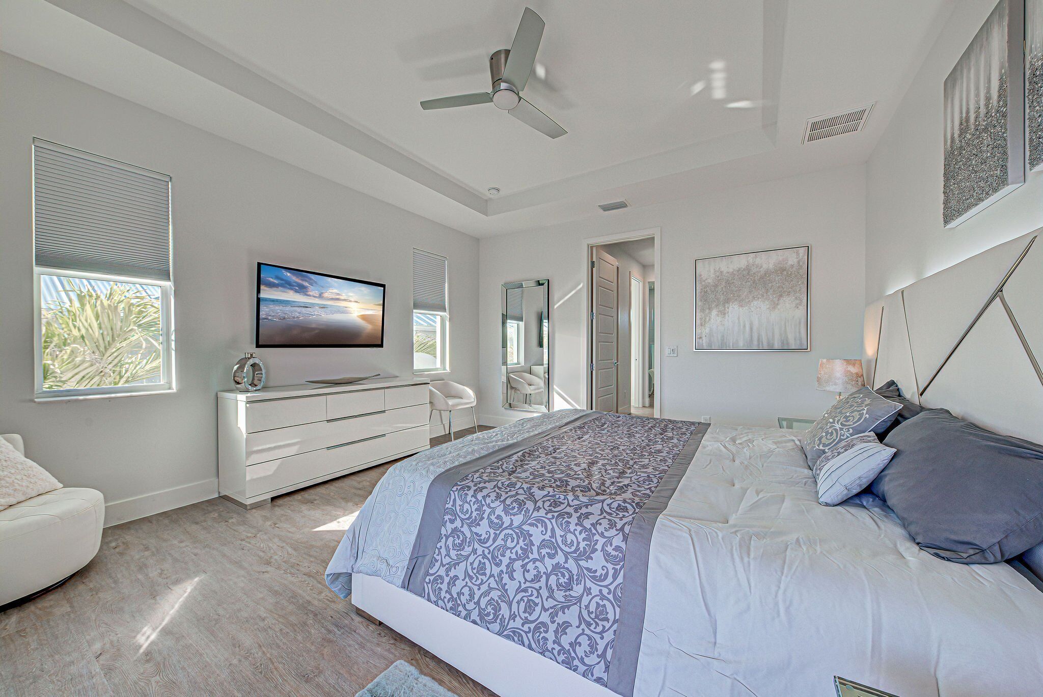 Camera da letto moderna con un letto grande, una TV a schermo piatto, una ventola a soffitto e vista sull'esterno dalla finestra.
