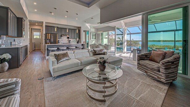 A spacious living area with a modern kitchen, a large glass dining table, and a comfortable seating arrangement. - Casa Riva | Lagoon Front | 2 Masters | Pool | Spa | Swim up Bar | Lounge (Port Charlotte)