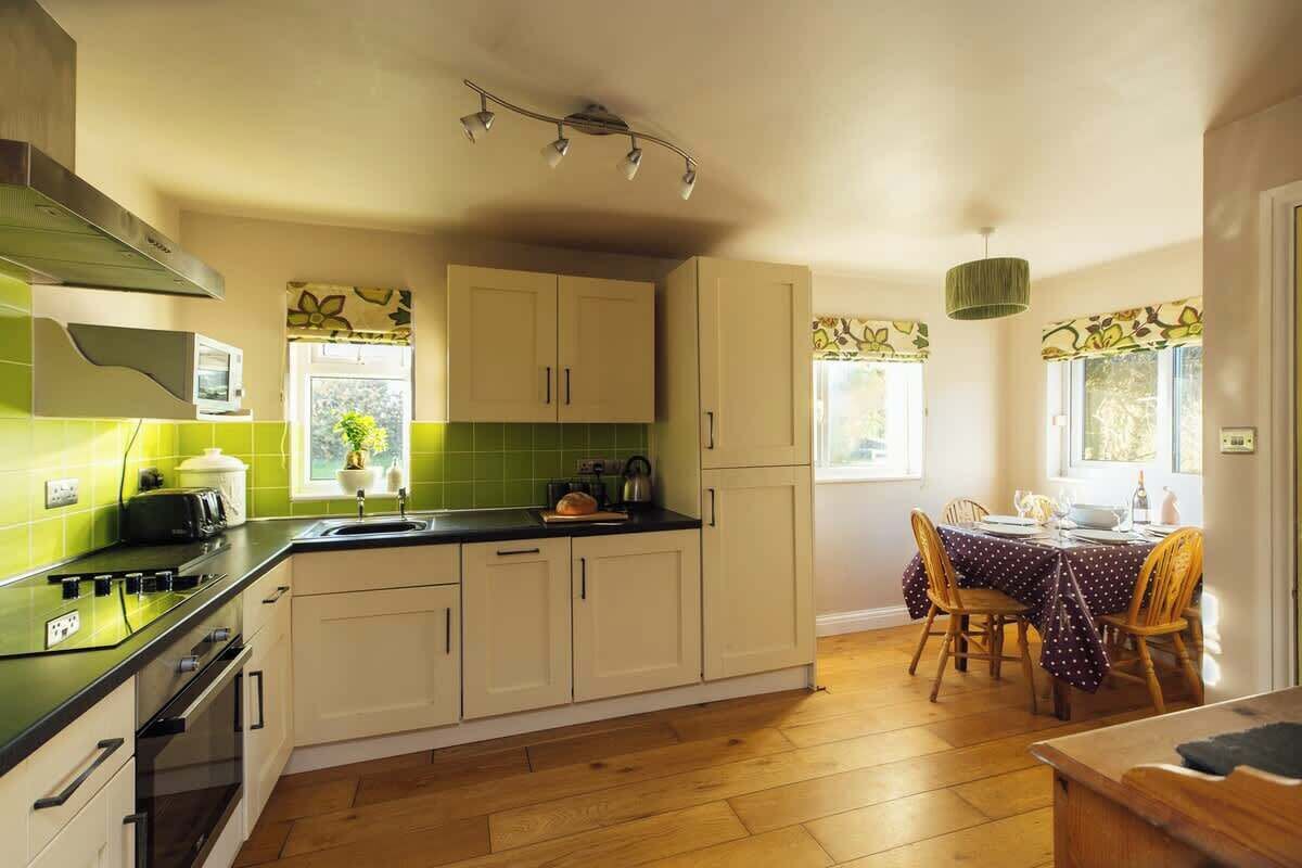 A compact kitchen with a stove, microwave, and a dining area with a table and chairs.