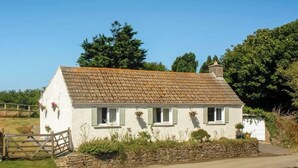 A white cottage with a tiled roof, stone foundation, and a wooden gate. - An idyllic Countryside Cottage Stay, near the Sea (Nolton Haven)