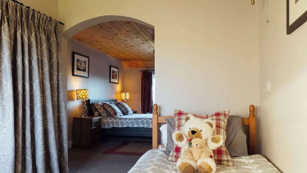A cozy bedroom with a bed, a teddy bear, and a nightstand with a lamp. - An idyllic Countryside Cottage Stay, near the Sea (Nolton Haven)
