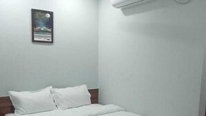 A bedroom with a bed, a ceiling fan, an air conditioning unit, and a framed picture on the wall.