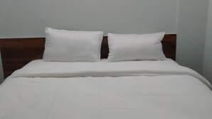 A neatly made bed with white bedding and a wooden headboard.