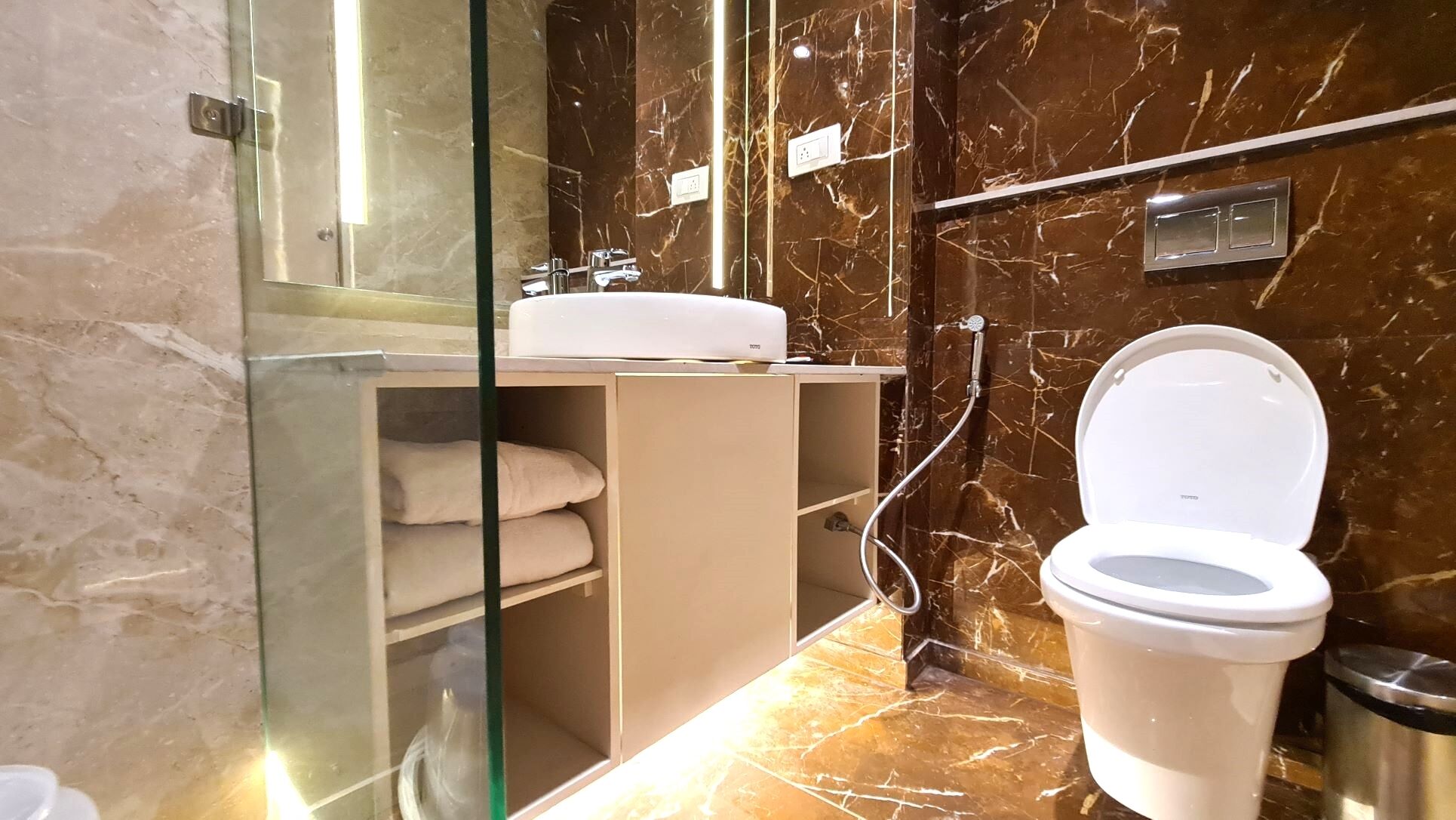 A modern bathroom with a glass-enclosed shower, a white toilet, and a marble-tiled floor.