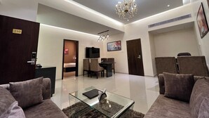 Una sala de estar moderna con una araña, un sofá, una mesa de centro de cristal y un televisor.