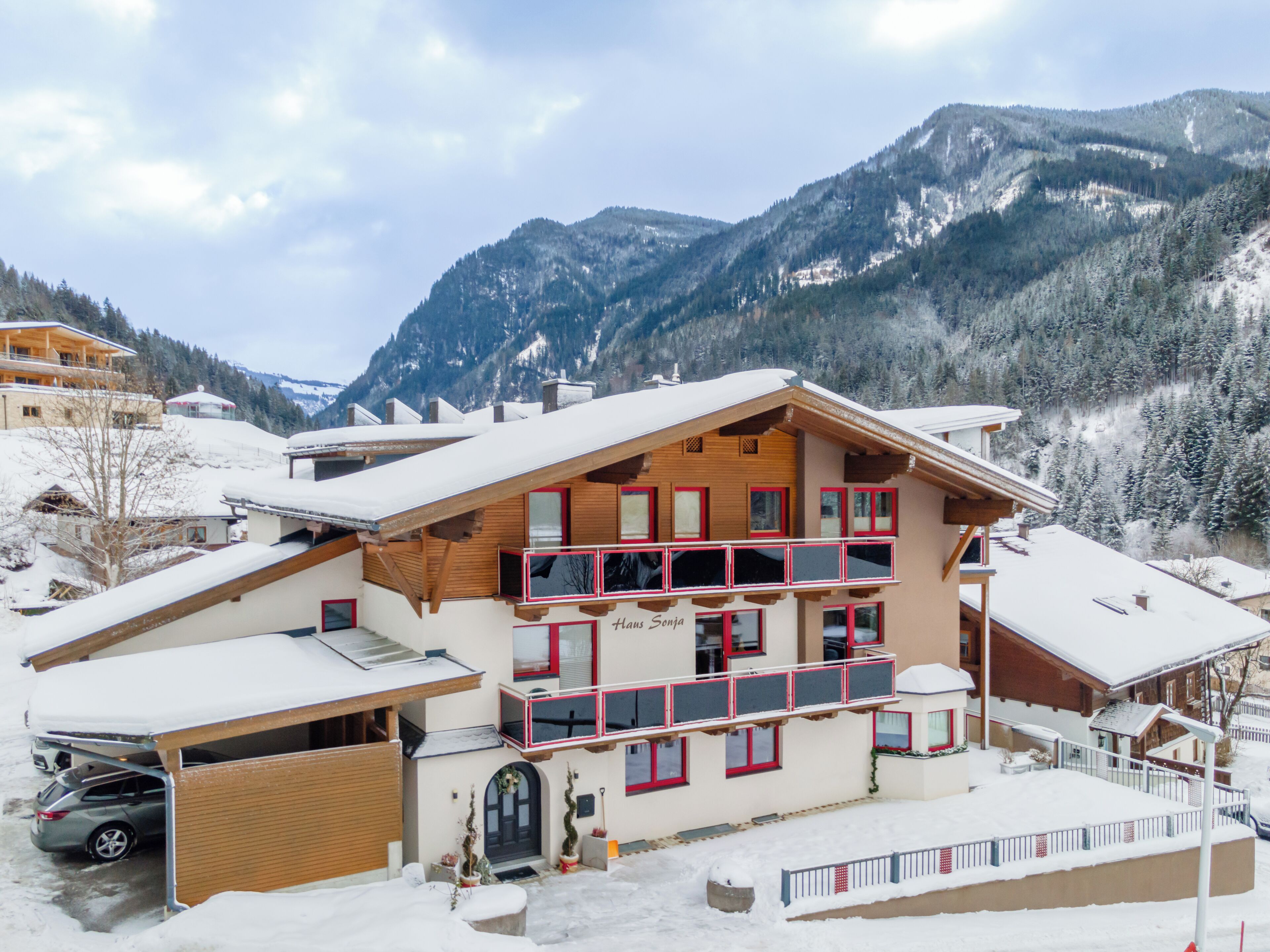 A multi-story building with a wooden facade, a balcony, and a snow-covered landscape in the background.
