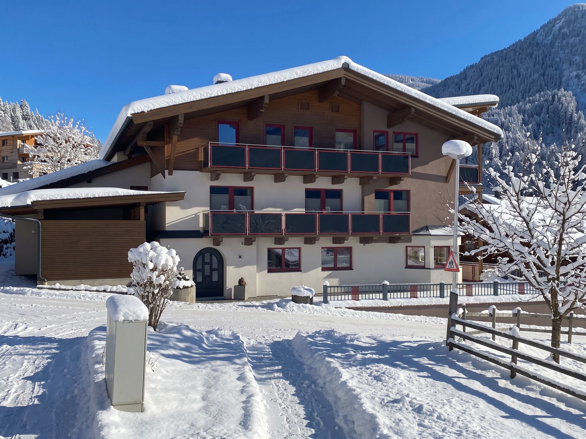 A multi-story building with balconies, a garage, and a snow-covered landscape.