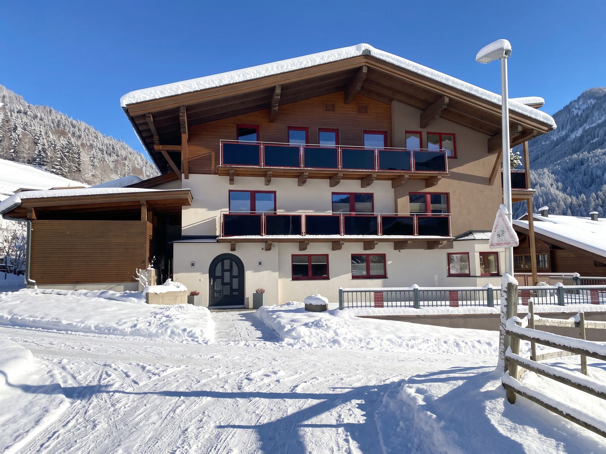 Ein mehrstöckiges Gebäude mit Balkonen, einer Garage und einer verschneiten Landschaft.