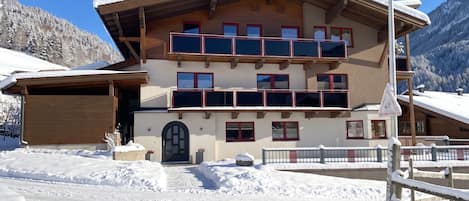 A multi-story building with balconies, a garage, and a snow-covered landscape.